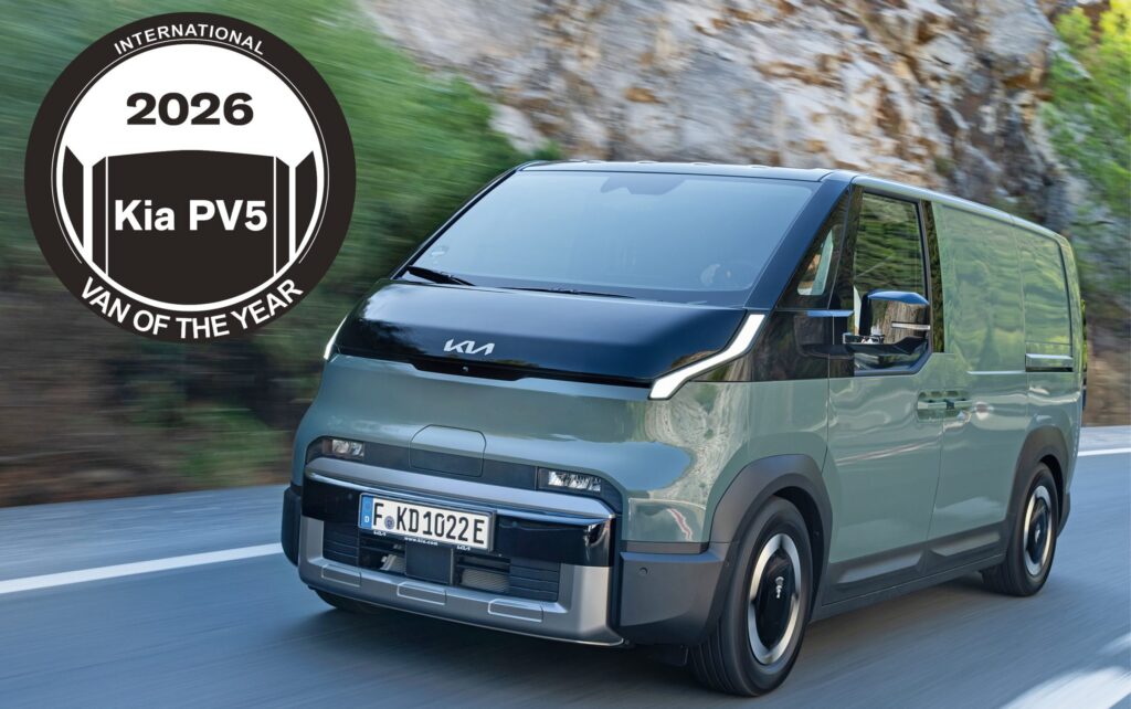Kia PV5 van driving on a highway with a large circular 2026 International Van of the Year badge on the left side of the image.